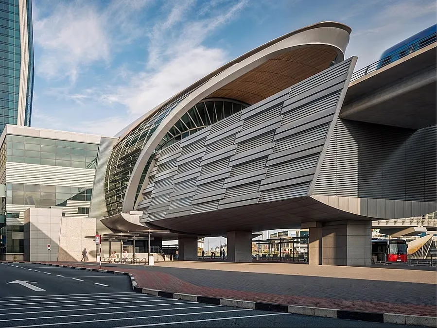 Crowds walk across the glass-walled pedestrian bridge connecting the Burj Khalifa metro station to Downtown Dubai.