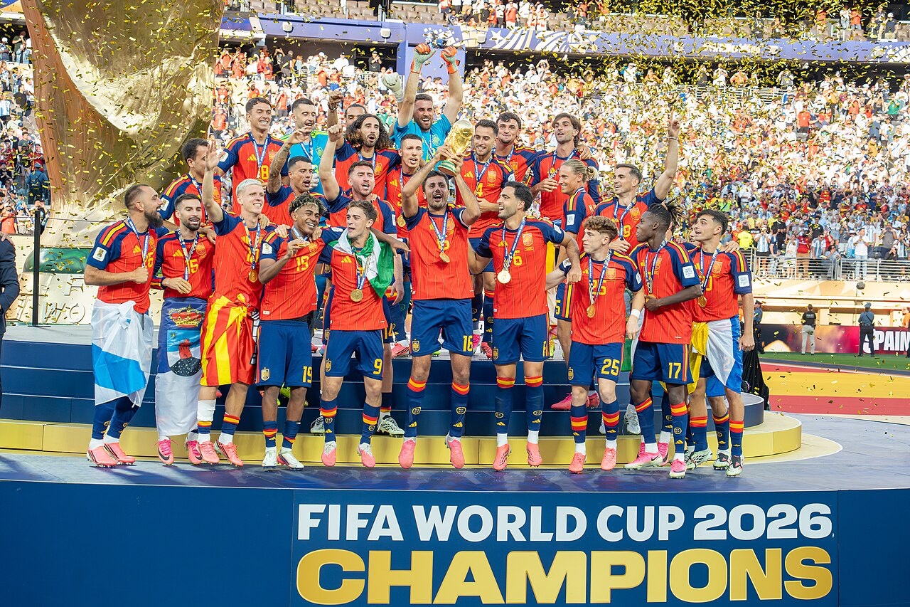Spanish players celebrate on the field while hoisting the gold World Cup trophy after defeating Argentina.