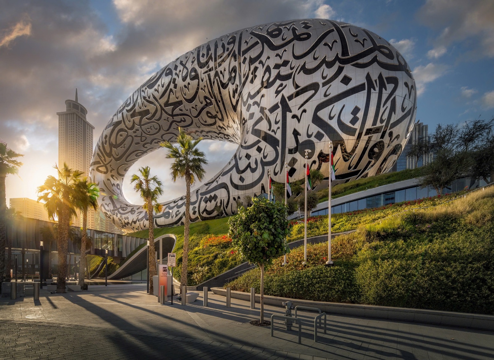 The torus-shaped Museum of the Future stands behind green palms under a clear blue sky in downtown Dubai.