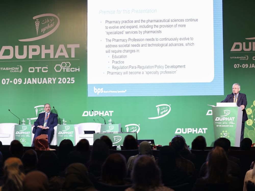 Crowds of professional attendees walk through a busy pharmaceutical exhibition hall at the Dubai World Trade Centre.