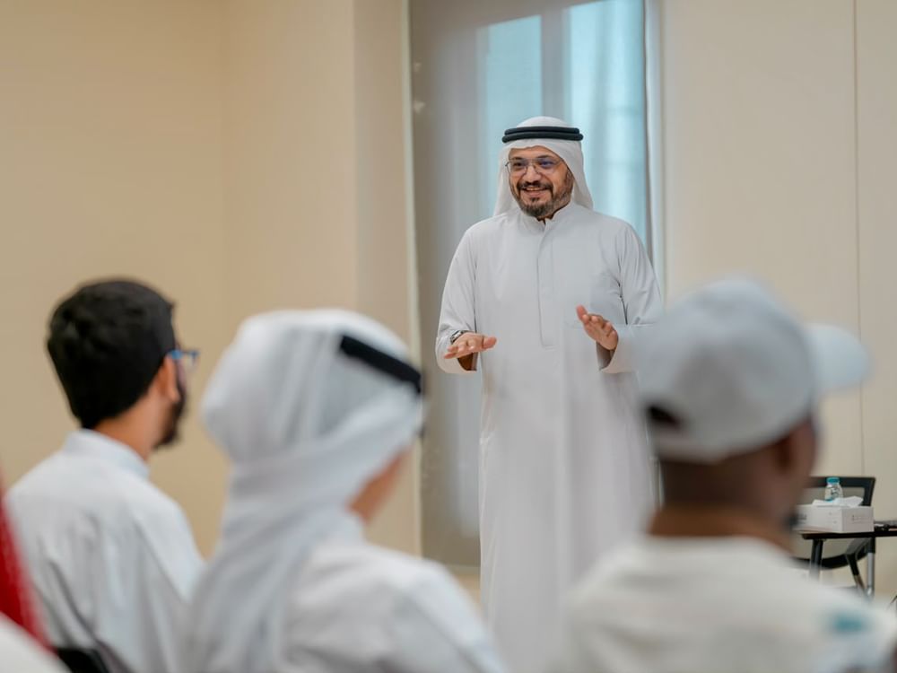 A group of people listens to a storyteller during a cultural heritage training session in Sharjah.