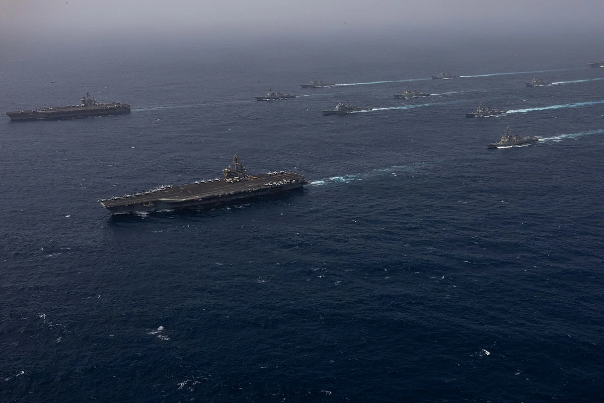 A U.S. Navy destroyer sails through dark blue waters in the Strait of Hormuz during a maritime security mission.