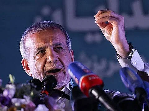 President Pezeshkian speaks at a podium before an Iranian flag as military tensions rise in the Middle East.