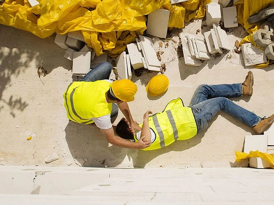A construction worker in a high-vis vest and hard hat reviews architectural blueprints on a sunny job site.