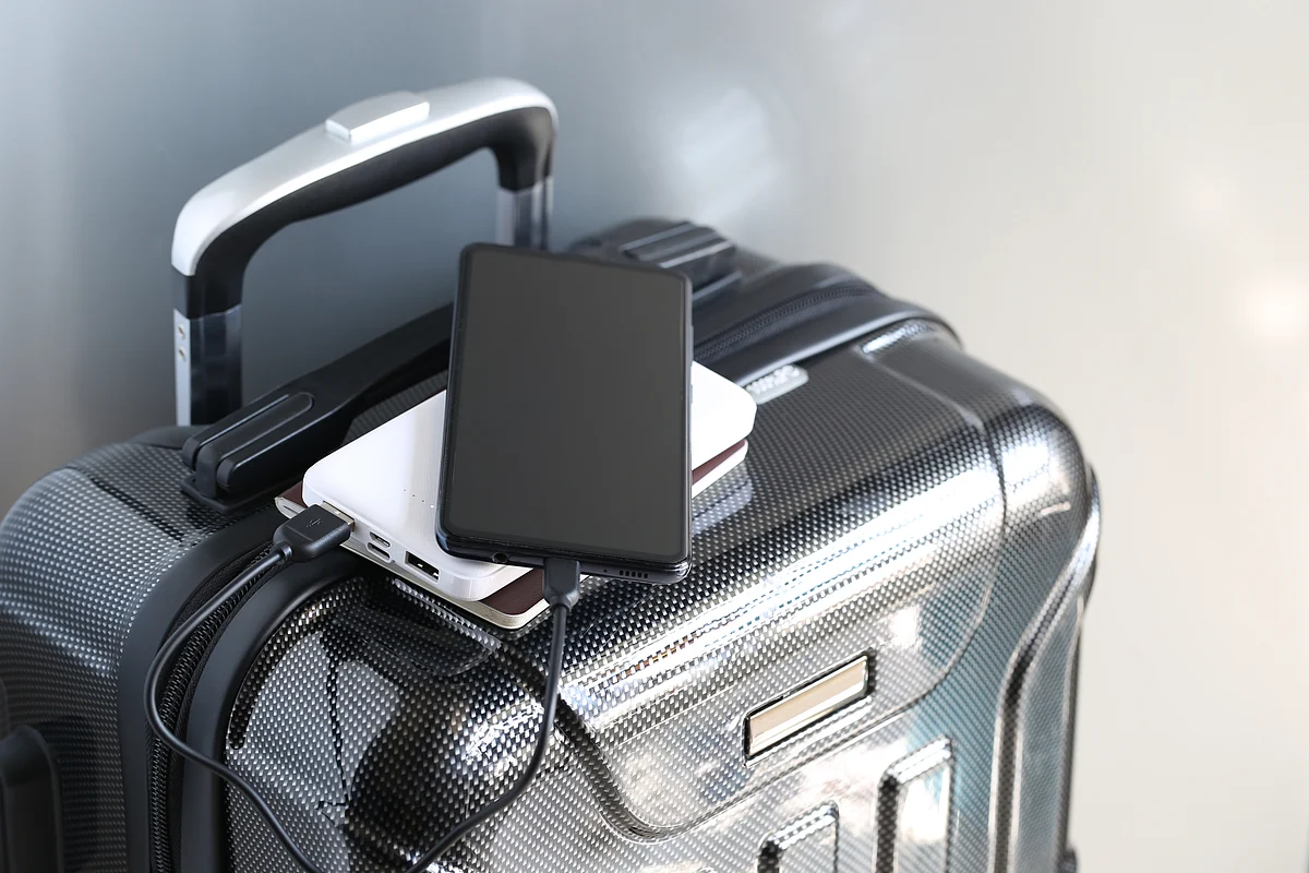A close-up of a damaged lithium-ion phone battery emitting grey smoke against a neutral studio background.