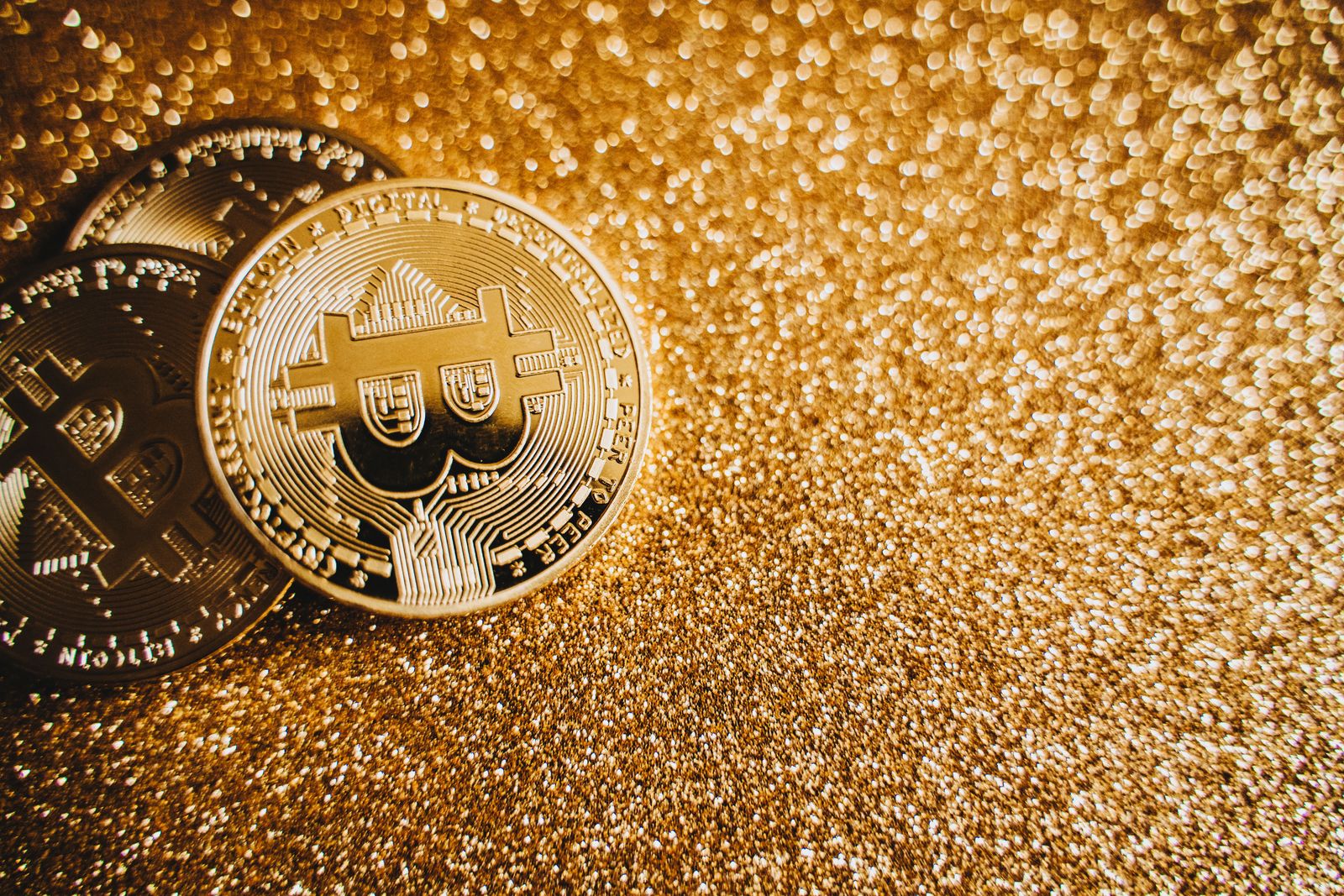 A digital gold bitcoin physical coin sits on a dark surface illuminated by glowing blue circuit patterns.