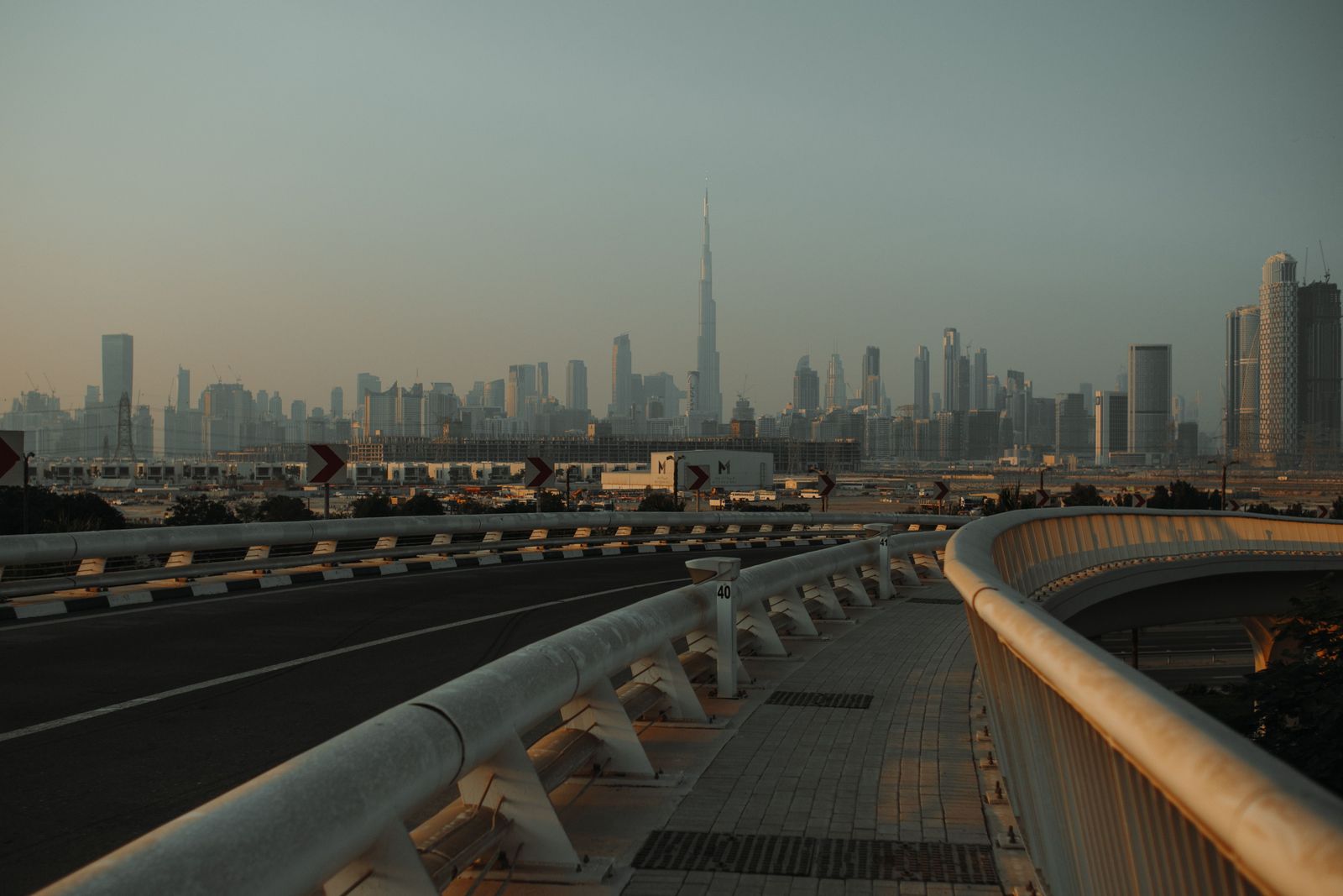 A sleek automated people mover train glides along a futuristic elevated track at Dubai Al Maktoum International Airport.