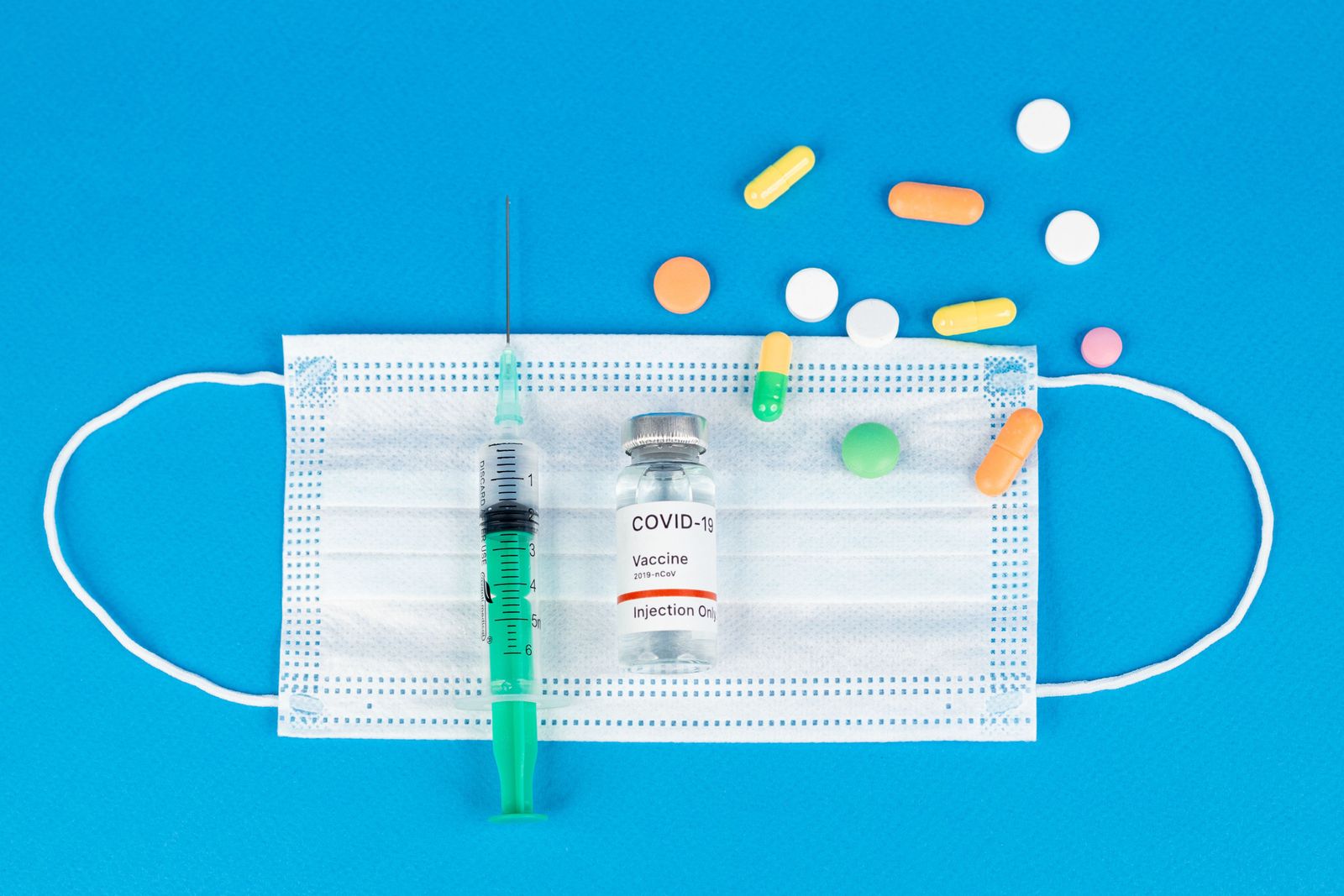 A pharmacist in a white lab coat organizes rows of boxed prescription medications on a pharmacy shelf.