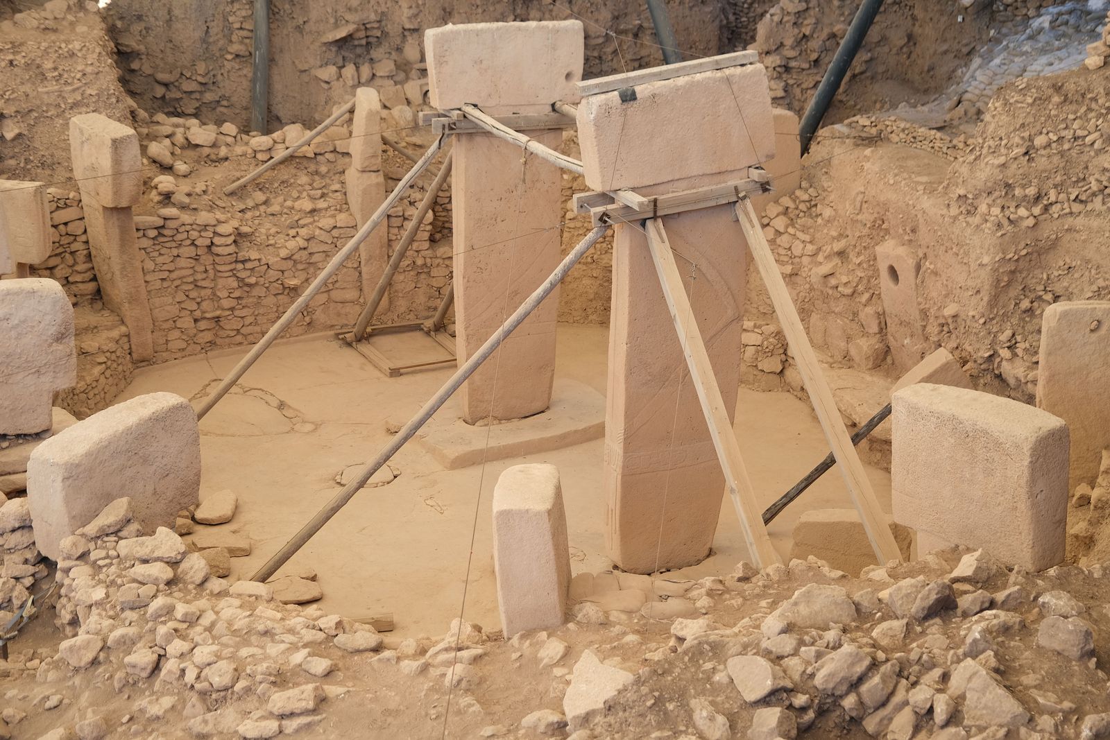 A close-up view shows weathered stone tools and pottery fragments unearthed at an ancient desert dig site.
