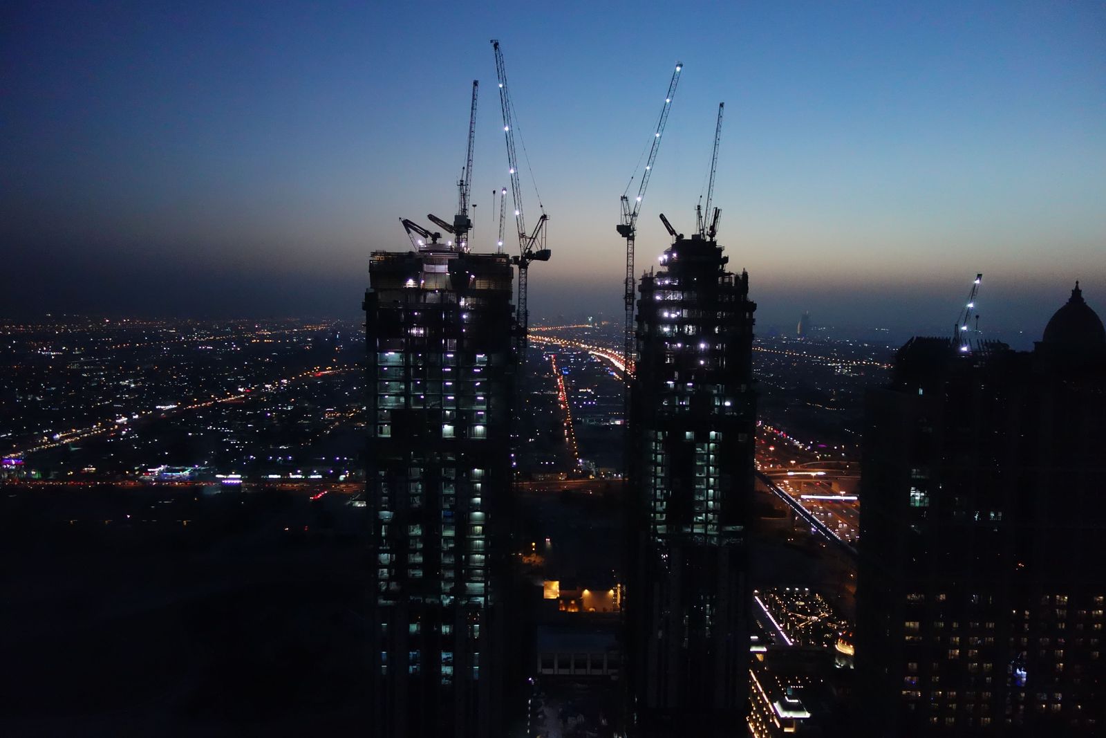 Two professionals in business attire shake hands in a modern office overlooking the Dubai International Financial Centre.