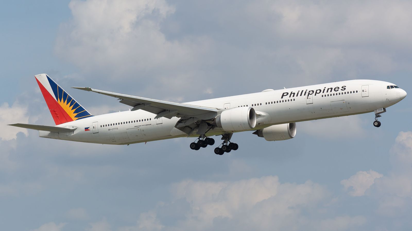 A Philippine Airlines passenger plane taxis on a sunny airport runway with its red and blue tail logo clearly visible.