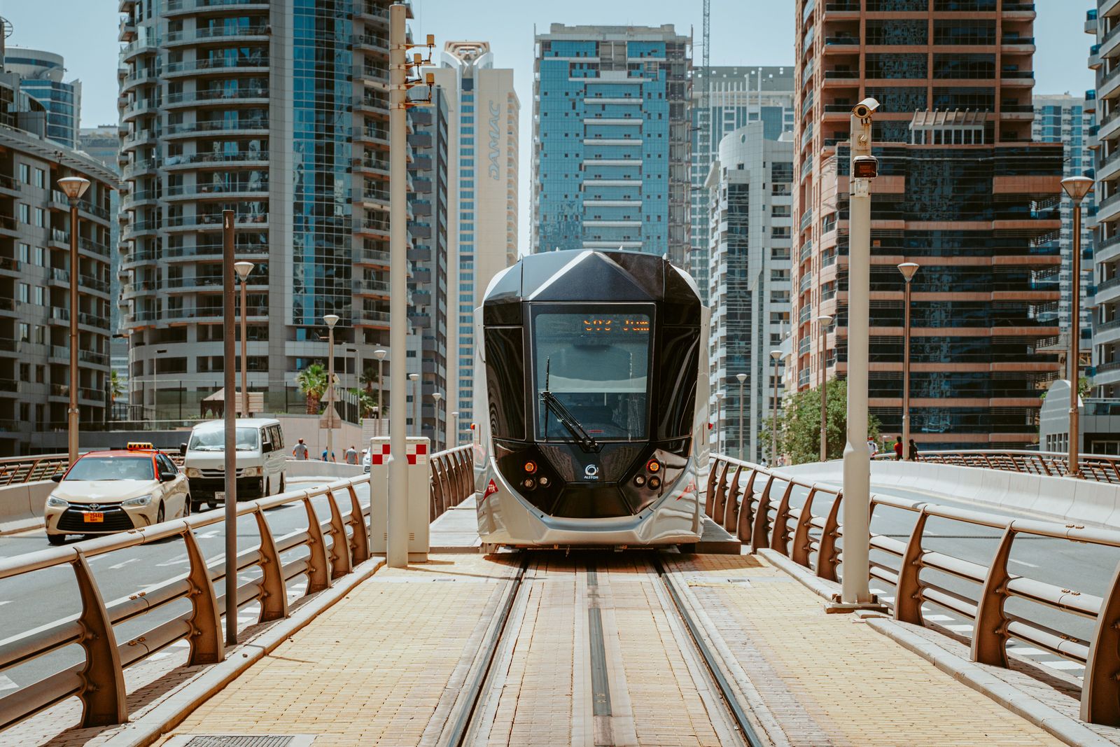 A sleek white Etihad Rail passenger train speeds along a desert track under a clear blue sky in the United Arab Emirates.