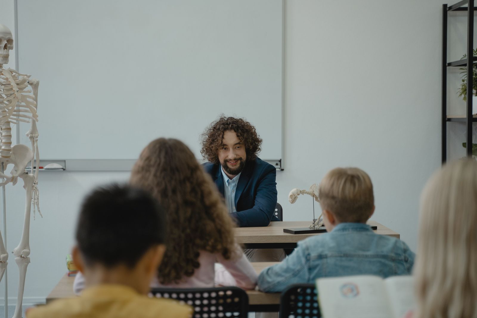 A teacher and young student smile while looking at a tablet together in a bright, modern classroom.