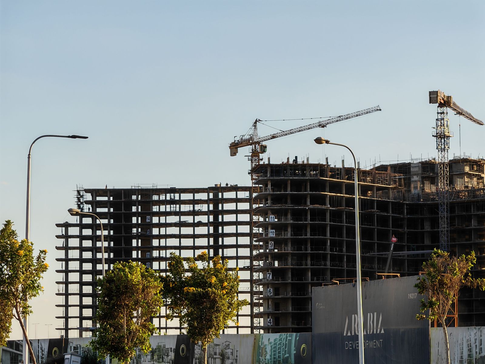 A modern residential high-rise stands against the Dubai skyline near the waterfront of the Meydan Horizon development.