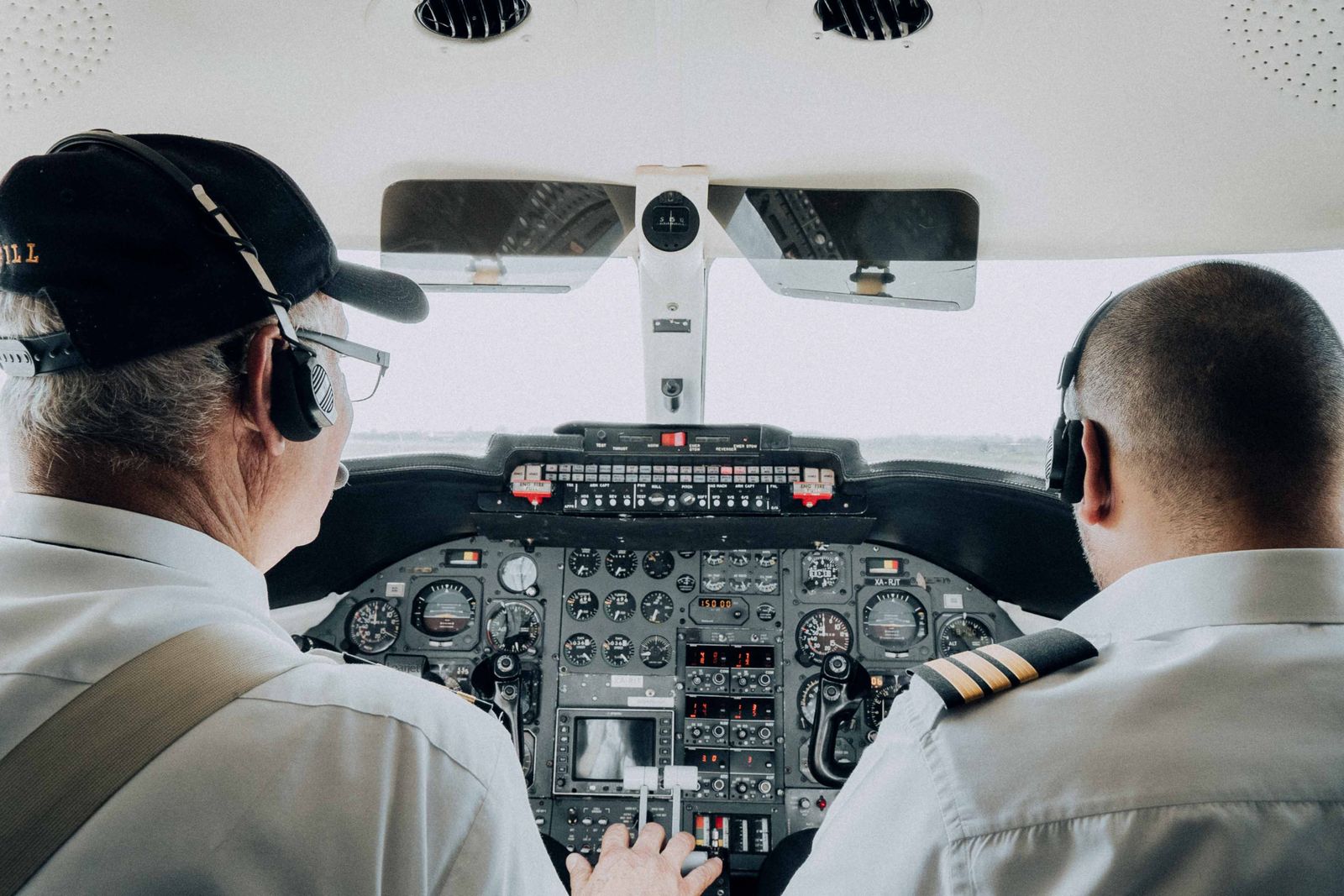 Captain Smit Machchhar smiles while wearing his pilot uniform and headset inside a commercial aircraft cockpit.