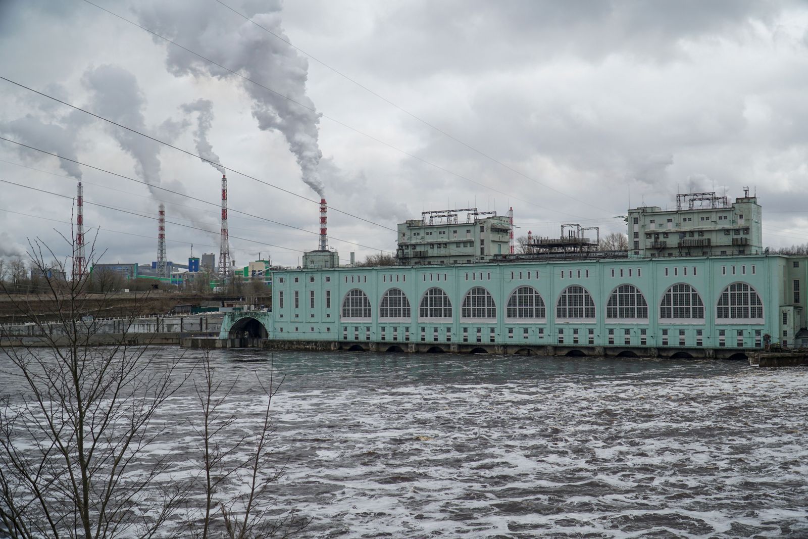 Industrial smoke billows from a Russian oil refinery against a hazy sky, representing the nation's energy sector.