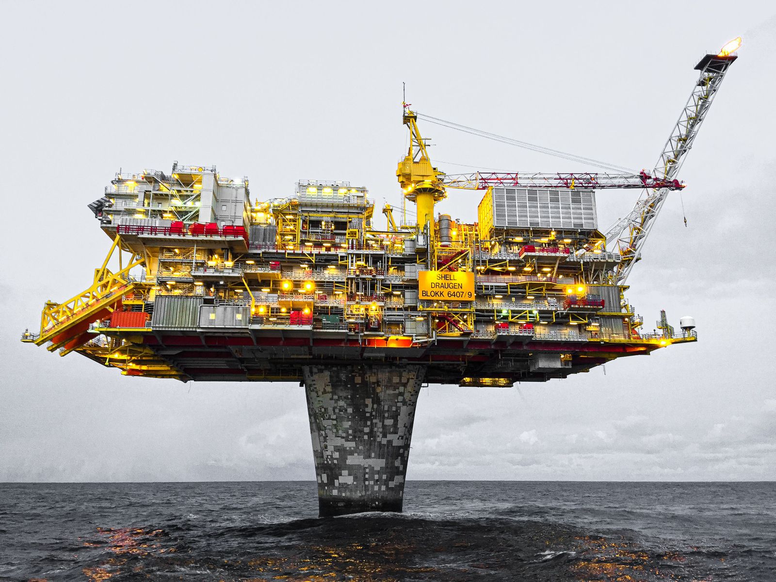 A mechanical pump jack extracts oil from a sun-drenched field against a clear, hazy horizon.