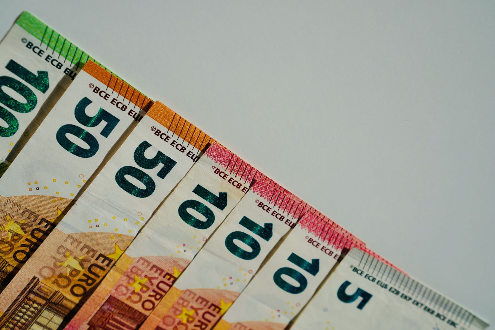 A golden euro symbol stands against a backdrop of blurred digital stock market charts showing downward red trends.