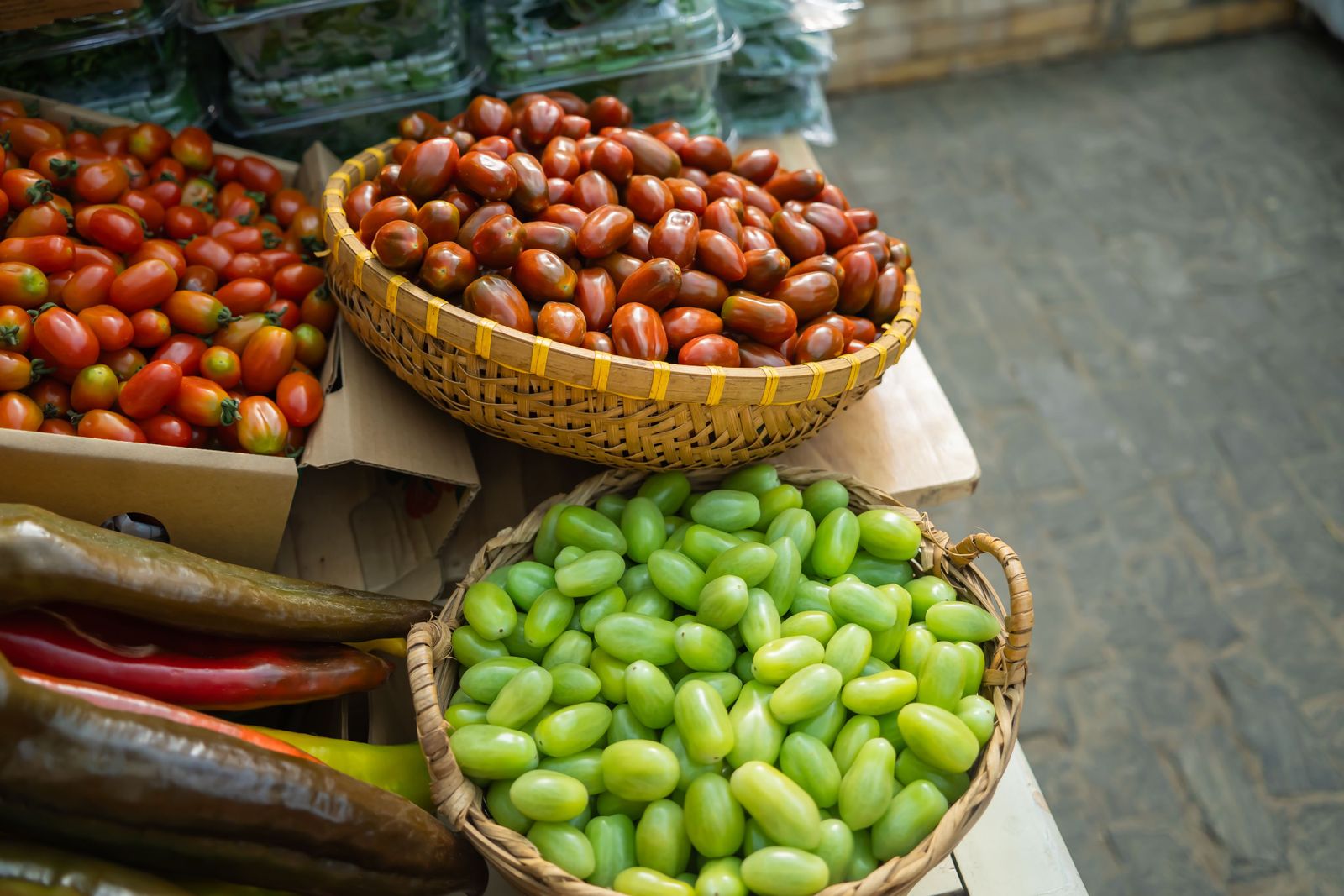 Fresh fruits and vegetables sit in wooden crates under a new brand sign inside a bright retail grocery store.