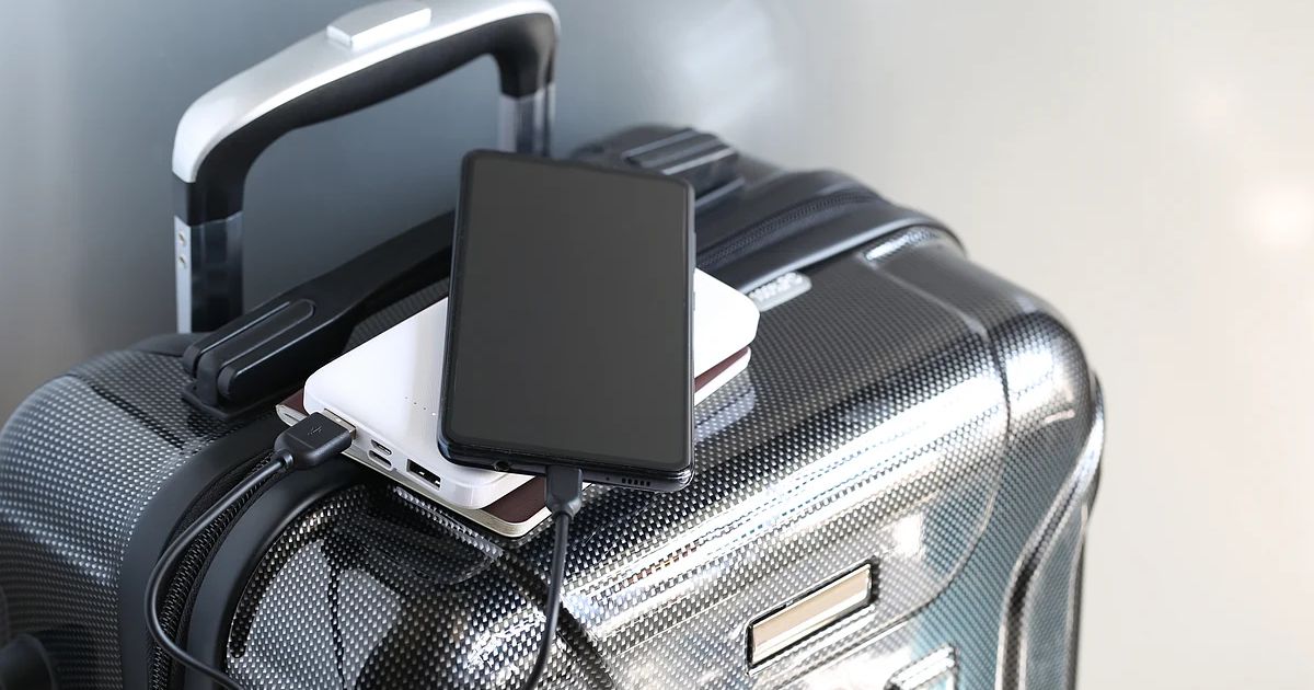 A close-up of a damaged lithium-ion phone battery emitting grey smoke against a neutral studio background.